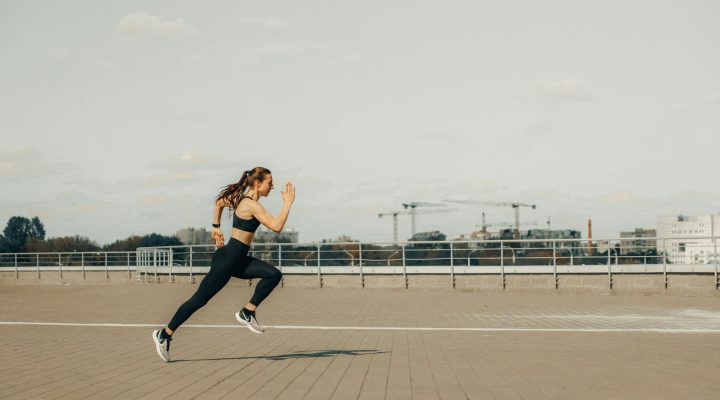 woman in black tank top and black pants jumping on brown wooden floor